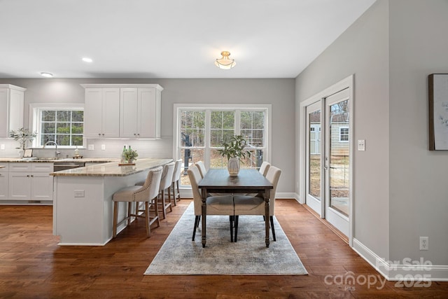 dining room featuring dark wood-type flooring, sink, and a healthy amount of sunlight