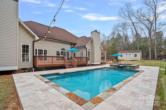 view of pool with a patio area, a storage unit, a deck, and an in ground hot tub