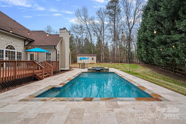 view of pool with an in ground hot tub, a deck, a patio, and a storage unit