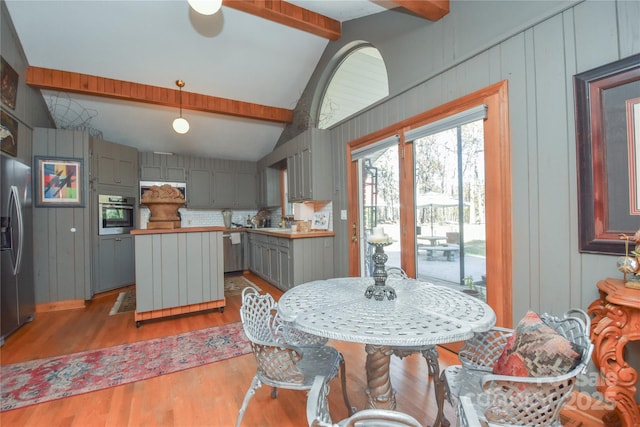 dining room with vaulted ceiling with beams and wood-type flooring