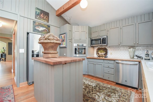 kitchen featuring wood counters, vaulted ceiling with beams, light wood-type flooring, and appliances with stainless steel finishes