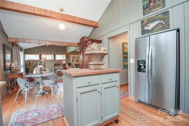 kitchen featuring pendant lighting, stainless steel refrigerator with ice dispenser, light hardwood / wood-style flooring, vaulted ceiling with beams, and butcher block counters