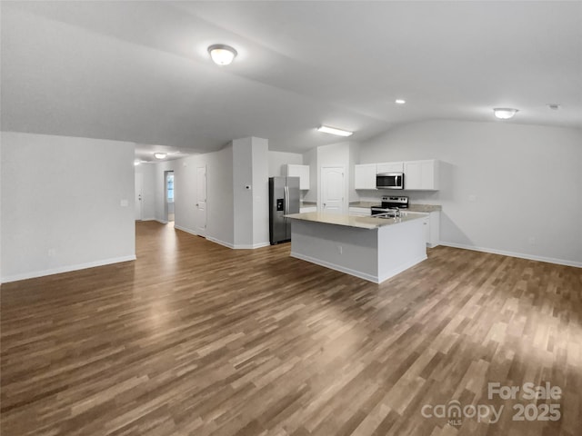 kitchen featuring appliances with stainless steel finishes, white cabinets, dark hardwood / wood-style flooring, an island with sink, and vaulted ceiling