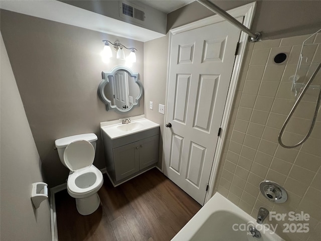 full bathroom with hardwood / wood-style floors, vanity, toilet, and tiled shower / bath