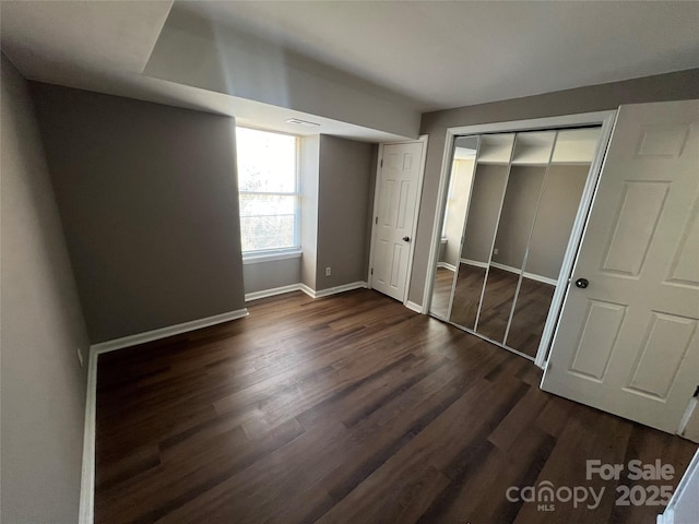 unfurnished bedroom with dark hardwood / wood-style floors and a closet