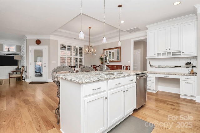 kitchen with a kitchen island with sink, sink, white cabinetry, and hanging light fixtures