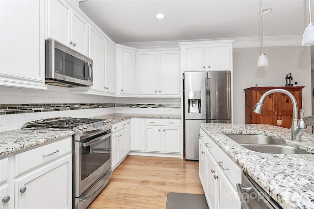 kitchen featuring sink, white cabinetry, crown molding, decorative light fixtures, and stainless steel appliances