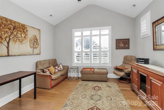 living area featuring vaulted ceiling and light hardwood / wood-style flooring