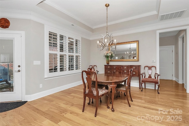 dining room with ornamental molding, light wood-style flooring, visible vents, and baseboards