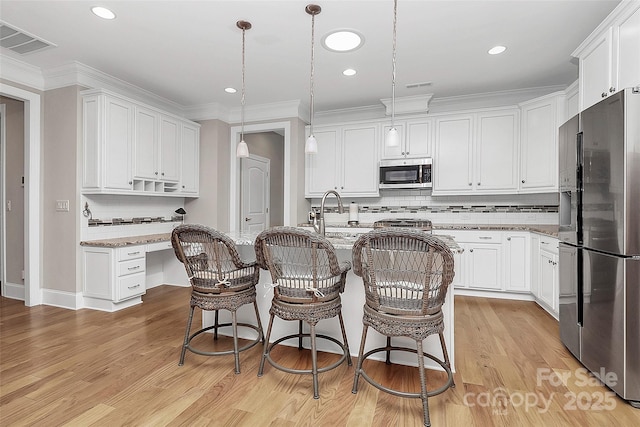 kitchen with stainless steel appliances, visible vents, light wood-style floors, white cabinetry, and light stone countertops