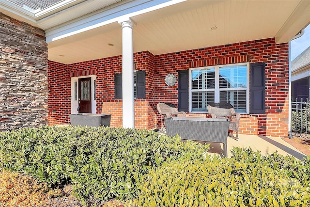 view of exterior entry featuring brick siding and a porch