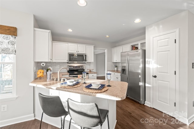 kitchen featuring white cabinets, stainless steel appliances, kitchen peninsula, and tasteful backsplash