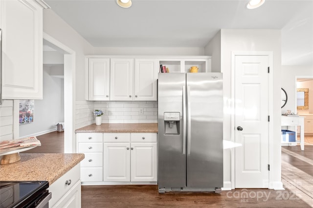 kitchen with dark wood-type flooring, stainless steel fridge, tasteful backsplash, light stone counters, and white cabinetry