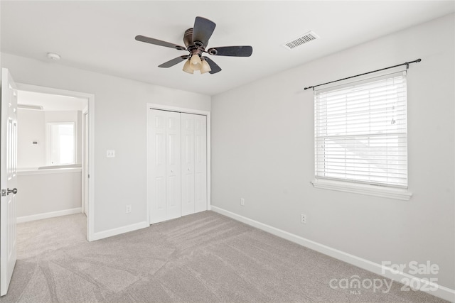 unfurnished bedroom featuring ceiling fan, a closet, and light colored carpet