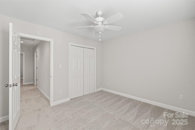 unfurnished bedroom featuring ceiling fan, light carpet, and a closet