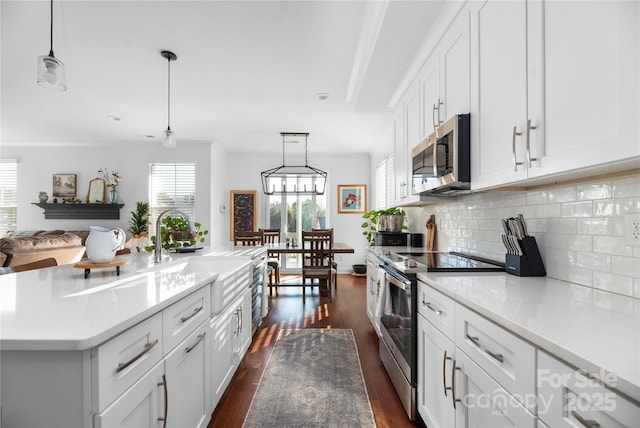 kitchen featuring hanging light fixtures, a center island with sink, stainless steel appliances, and sink