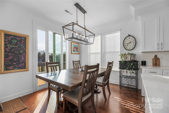 dining area with a notable chandelier, dark hardwood / wood-style floors, and crown molding