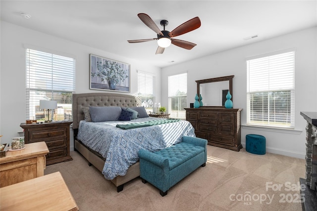 bedroom featuring ceiling fan, light carpet, and multiple windows