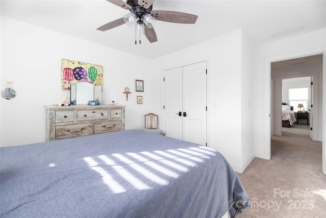 bedroom with ceiling fan, a closet, and light colored carpet