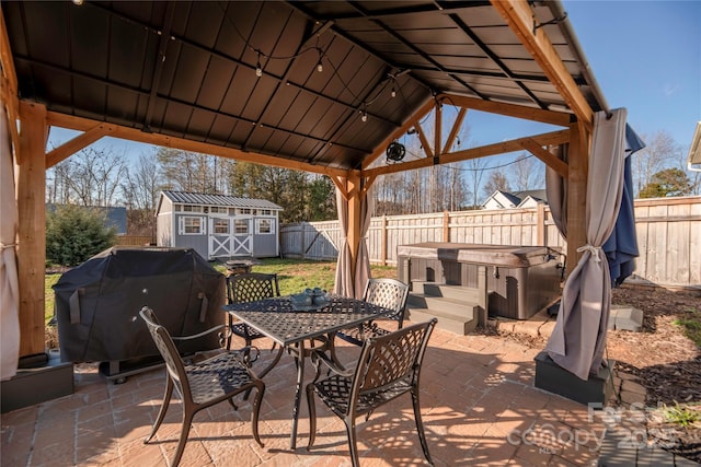 view of patio / terrace featuring a gazebo, a storage unit, area for grilling, and a hot tub