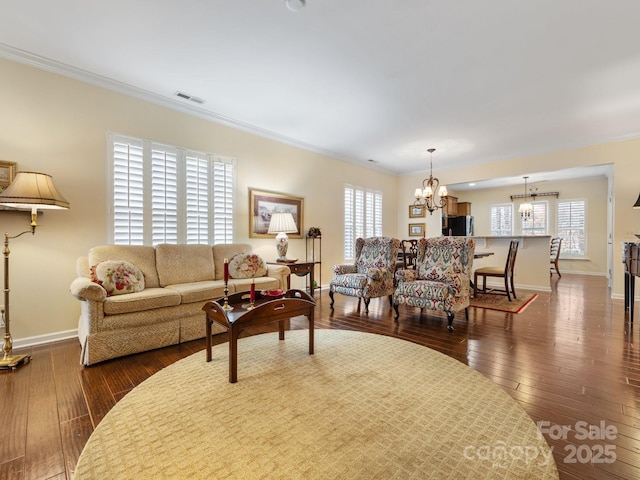 living room featuring dark hardwood / wood-style flooring, ornamental molding, and an inviting chandelier