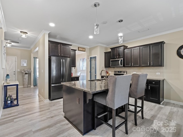 kitchen featuring light wood-style flooring, appliances with stainless steel finishes, a sink, and ornamental molding