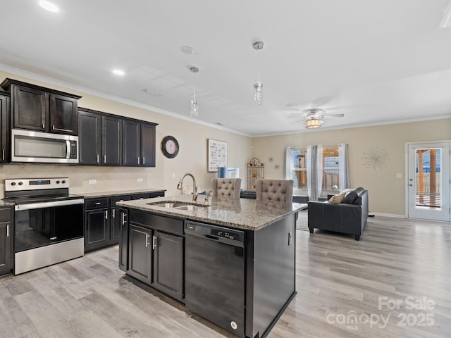 kitchen with light wood finished floors, light stone counters, ornamental molding, stainless steel appliances, and a sink