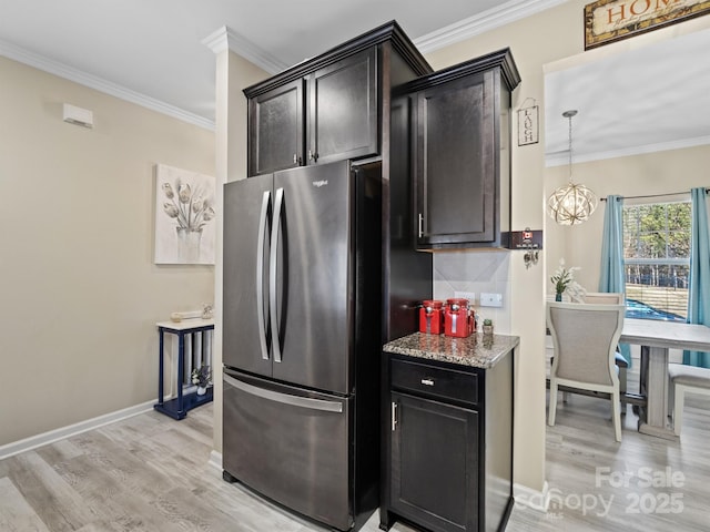 kitchen with ornamental molding, light wood-style flooring, freestanding refrigerator, and light stone countertops