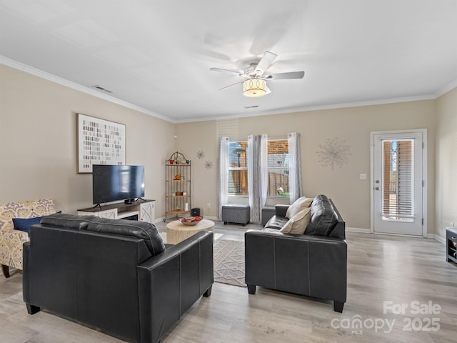 living area featuring ornamental molding, light wood-style floors, visible vents, and a healthy amount of sunlight