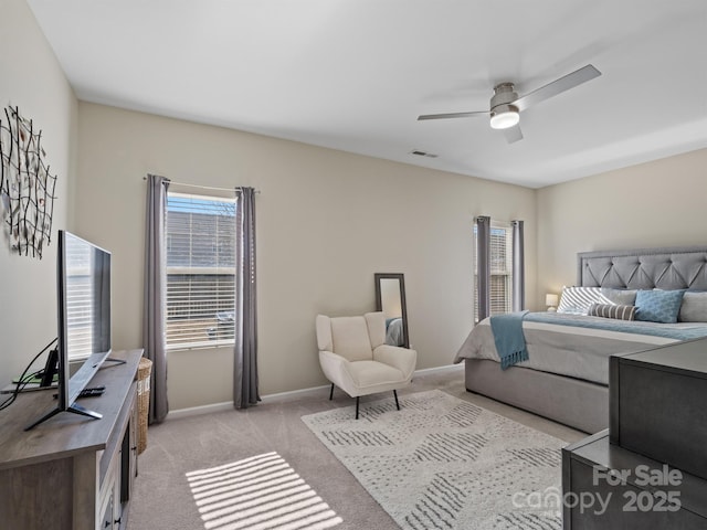 bedroom with ceiling fan, multiple windows, baseboards, and light colored carpet