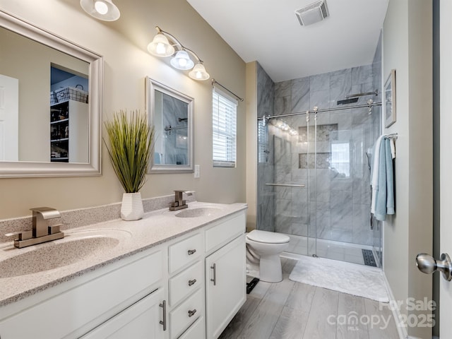 full bath featuring toilet, double vanity, a sink, and visible vents