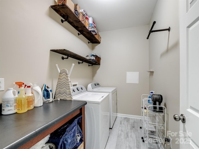 clothes washing area with light wood-style floors, washer and dryer, laundry area, and baseboards