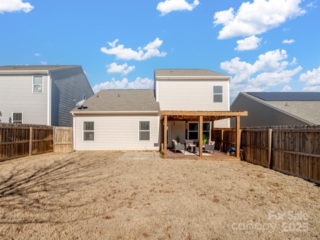 rear view of property featuring a shingled roof, a patio area, and a fenced backyard