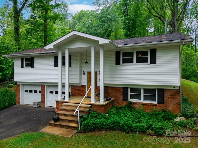 bi-level home featuring a garage, brick siding, and driveway