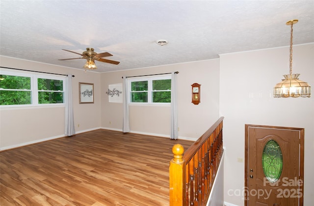 foyer featuring light wood-type flooring, a ceiling fan, baseboards, and a textured ceiling