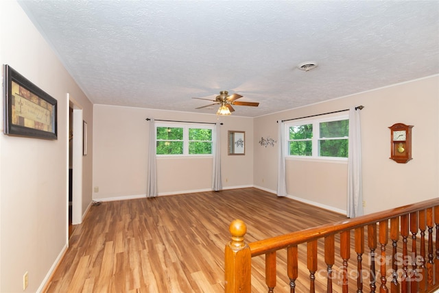 spare room with light wood-style floors, baseboards, visible vents, and a wealth of natural light