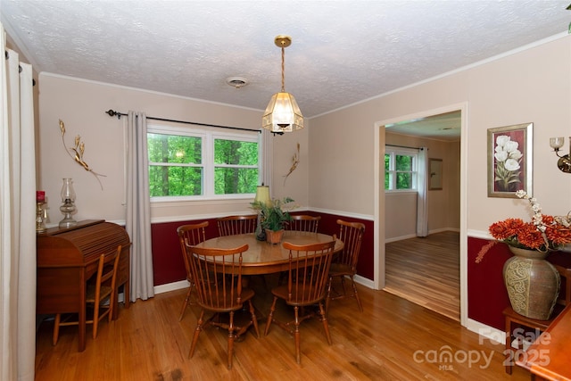 dining space featuring visible vents, ornamental molding, a textured ceiling, wood finished floors, and baseboards