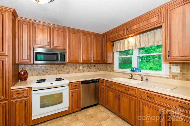 kitchen featuring stainless steel appliances, light countertops, brown cabinets, and a sink