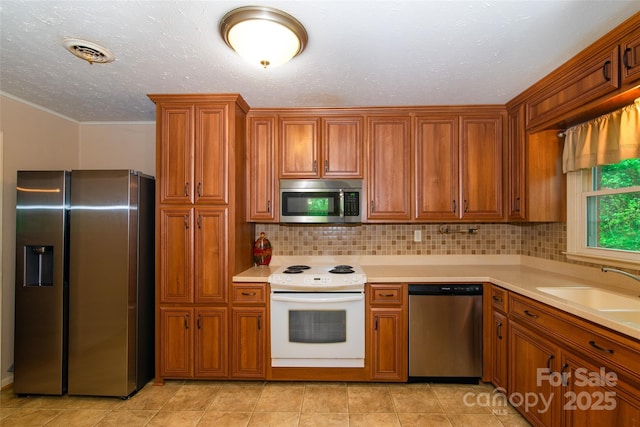 kitchen with appliances with stainless steel finishes, brown cabinetry, and visible vents