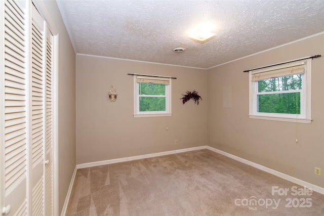 carpeted spare room with crown molding, plenty of natural light, and baseboards