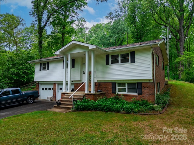 bi-level home with a garage, a front yard, aphalt driveway, and brick siding