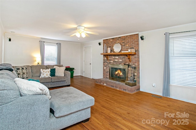 living room featuring hardwood / wood-style floors, crown molding, a fireplace, and ceiling fan