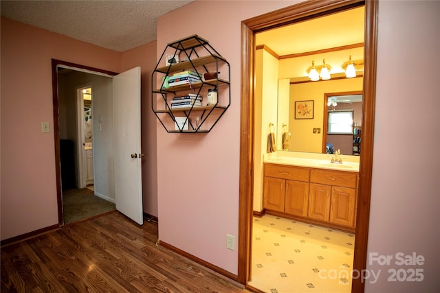 hallway with dark hardwood / wood-style floors, sink, and a textured ceiling