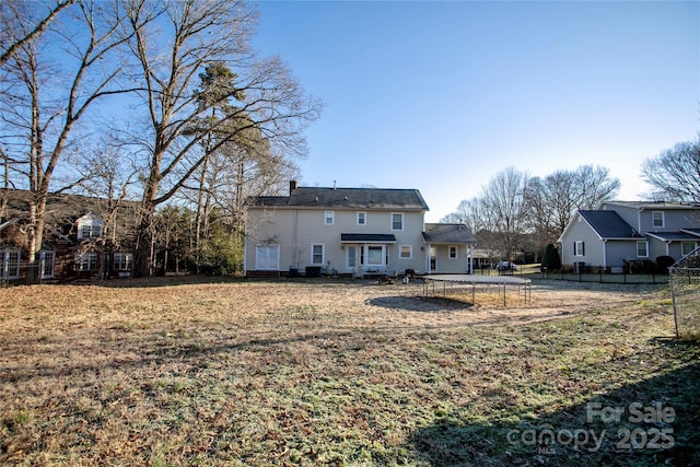 rear view of property with a yard and a trampoline