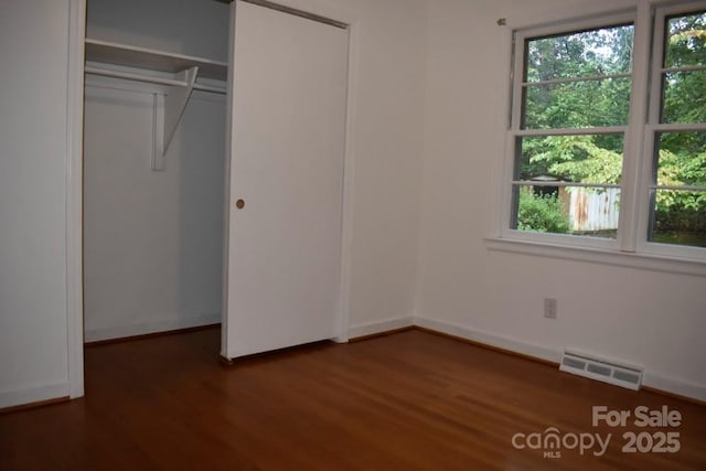 unfurnished bedroom with dark hardwood / wood-style flooring and a closet