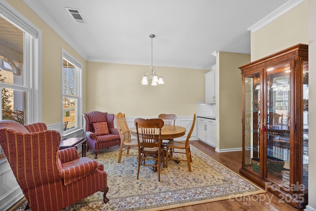 dining area featuring dark wood-type flooring, a chandelier, and ornamental molding