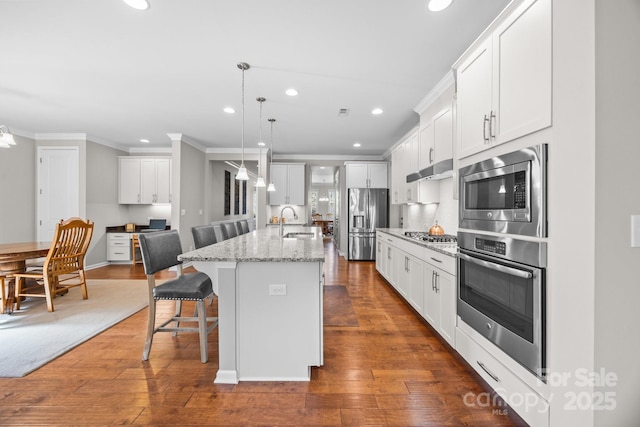 kitchen with white cabinets, sink, an island with sink, appliances with stainless steel finishes, and a breakfast bar area