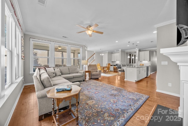 living room featuring ceiling fan, plenty of natural light, light hardwood / wood-style floors, and ornamental molding