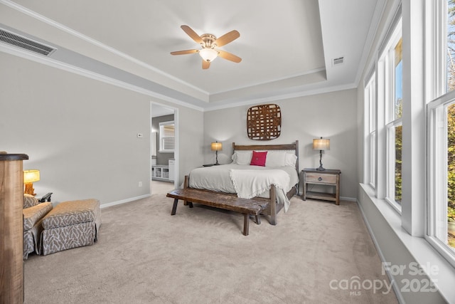 bedroom with light colored carpet, a raised ceiling, ceiling fan, crown molding, and connected bathroom