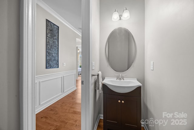 bathroom featuring vanity, hardwood / wood-style flooring, and ornamental molding